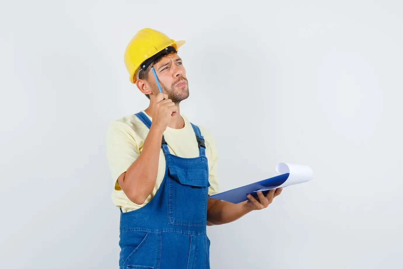 Front-facing view of a young engineer in uniform holding a pencil and a clipboard, appearing pensive.