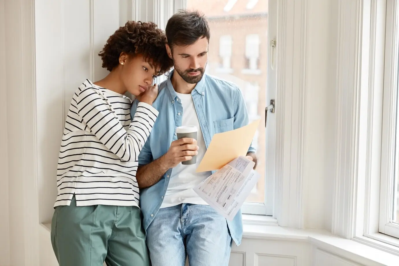An African American woman and her bearded Caucasian husband discuss the terms of a new contract with an employee.